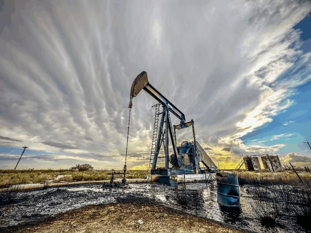 an abandoned oil well sitting on land with oil pollution all around it.